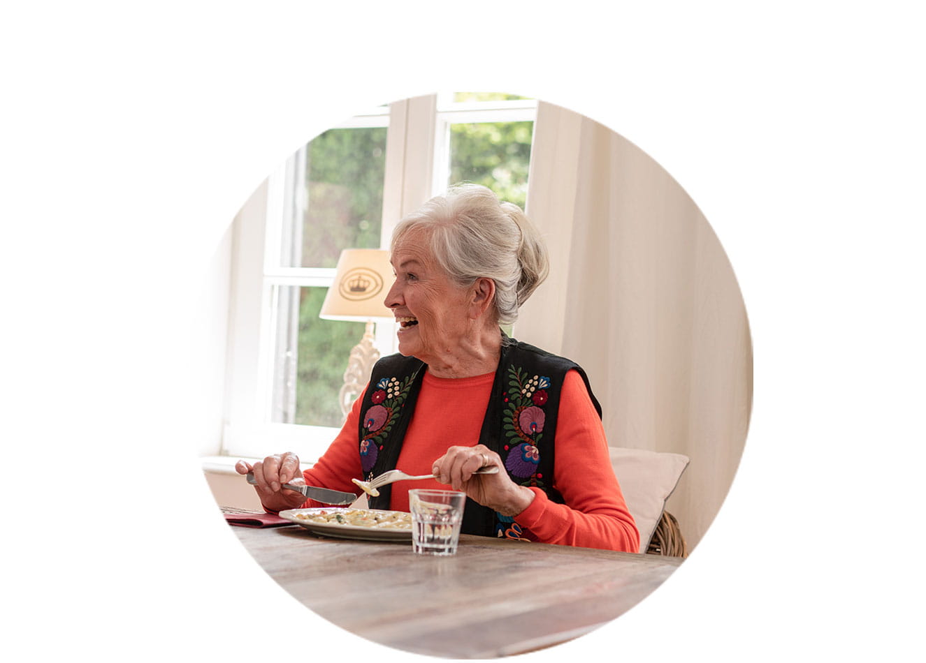 lachende ältere Frau am Tisch beim Essen