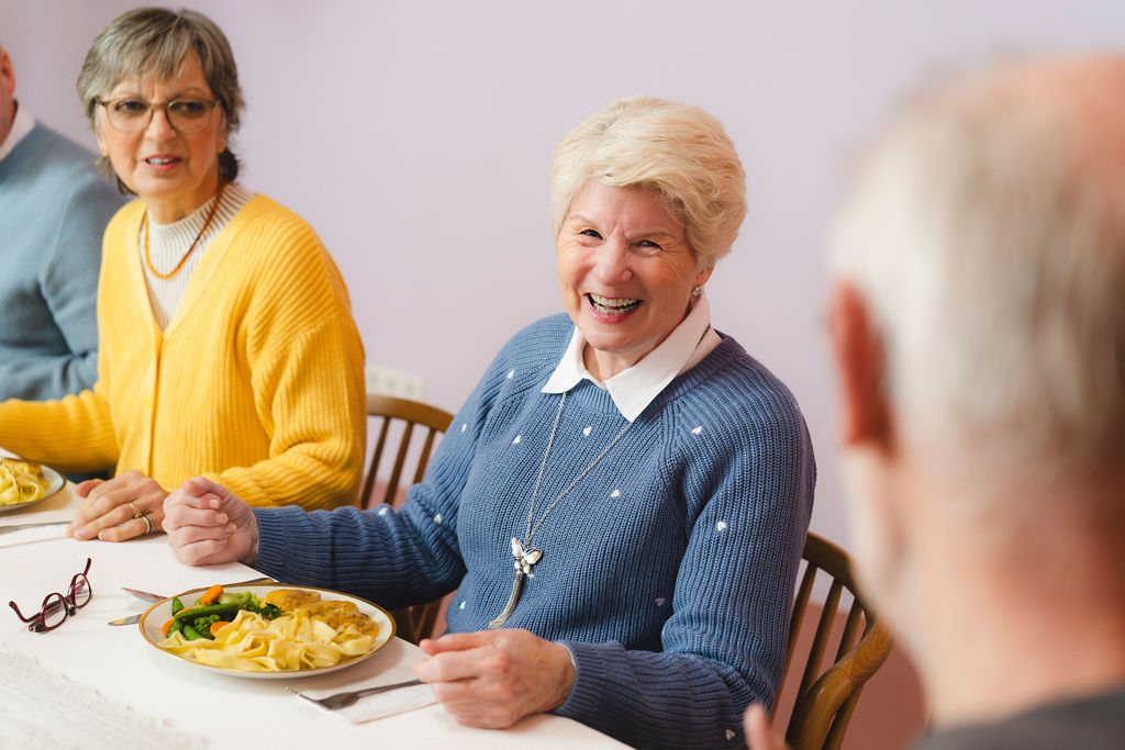 Personen sitzen lachend am Tisch und Essen