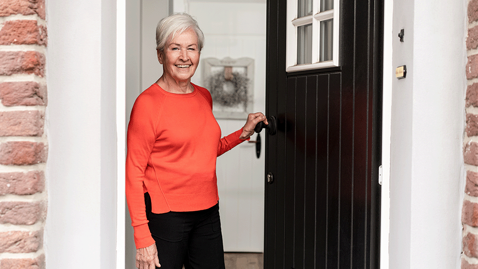 eine lachende Frau öffnet die Haustür