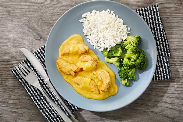 Hähnchenfiletstücke in gelber Currysoße, dazu Reis und Brokkoli