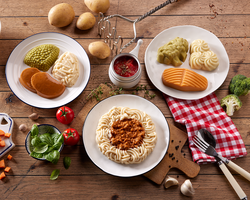 Drei pürierte Menüs in geformter Optik: Spaghetti Bolognese, pürierter Lachs in Soße, pürierte Gemüseschnitte in Tomatensoße